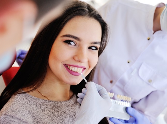 Dentist holding row of veneers next to a smiling patient
