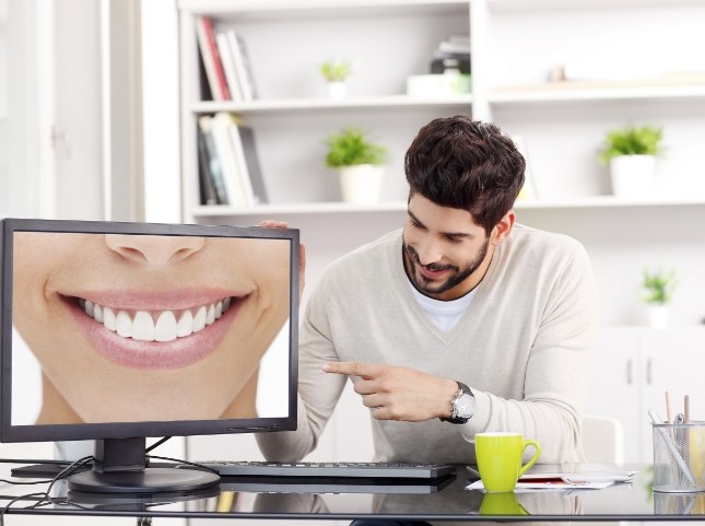 Man pointing to computer screen showing close up of smile with flawless teeth
