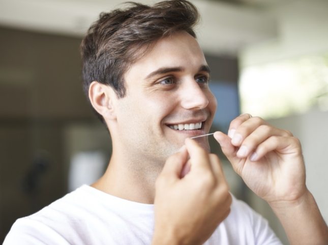 Man smiling while flossing his teeth