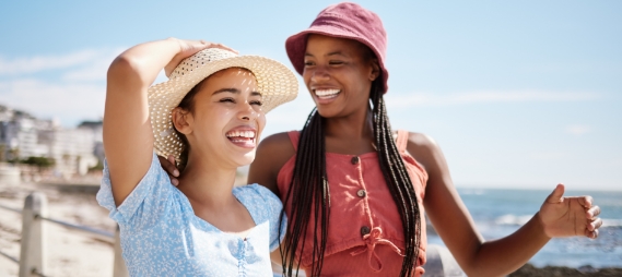 Two women in sunhats smiling at the beach