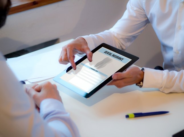Two people looking at dental insurance information on tablet