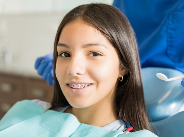 Teenage girl with braces smiling in dental chair