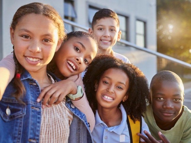 Five kids smiling in front of school