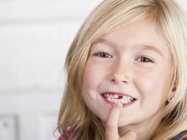 Child pointing to their mouth with one missing tooth