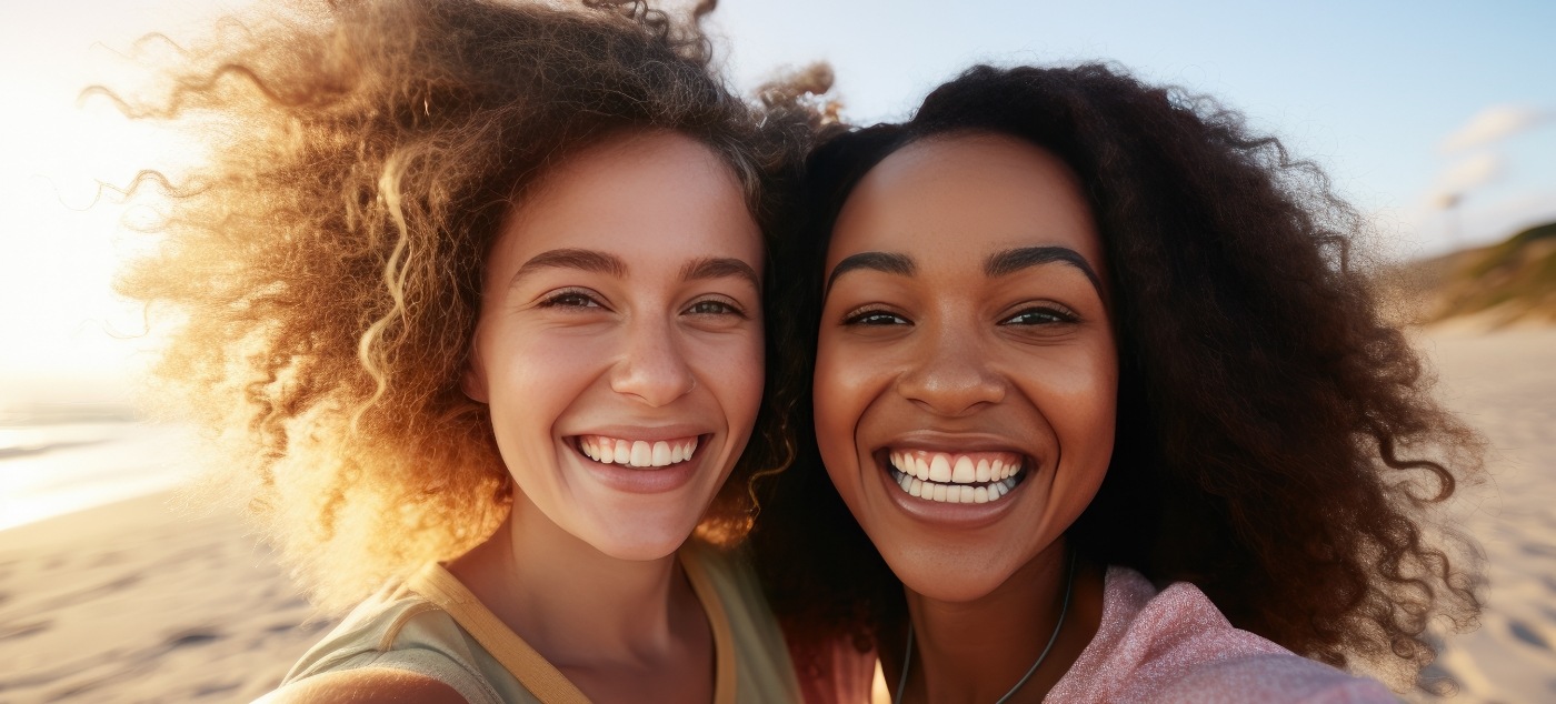 Two young women smiling with sunset in background