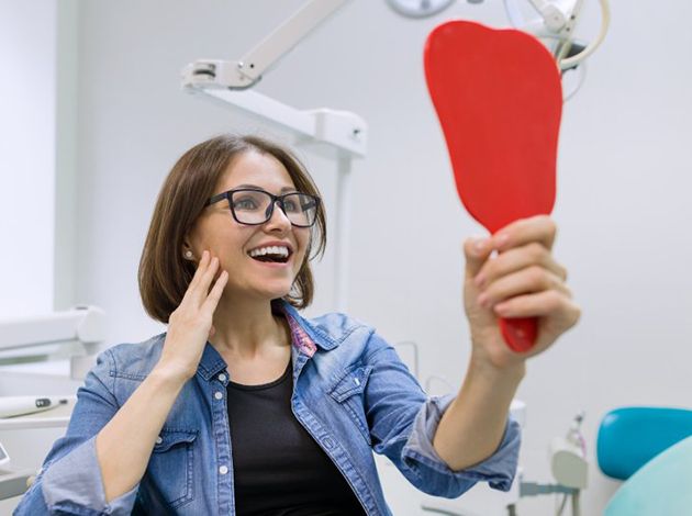 a patient checking her smile with a mirror
