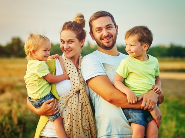 Smiling family of four in grassy field