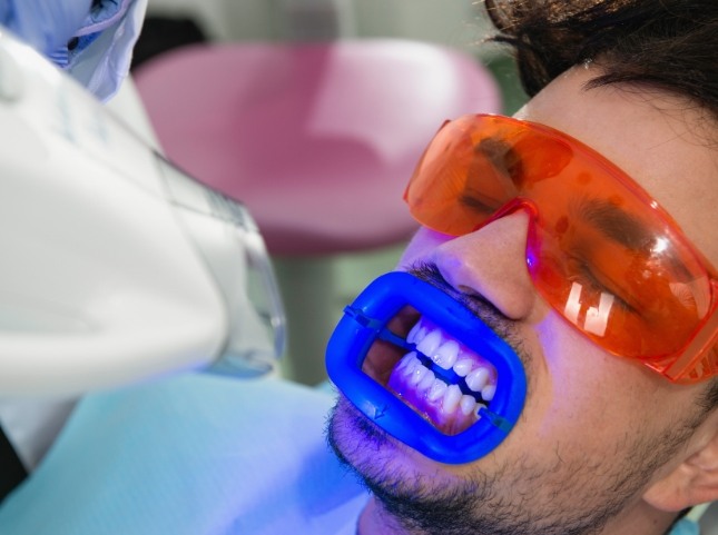 Man getting professional teeth whitening in dental chair