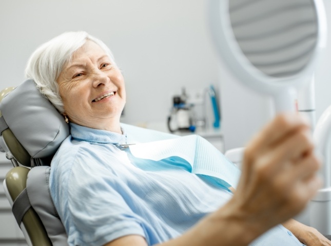 Dental patient admiring her smile in a mirror