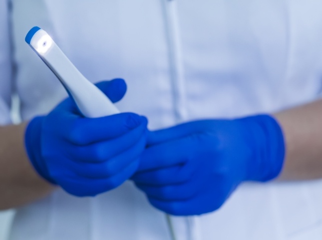 Dental professional holding a thin white intraoral camera