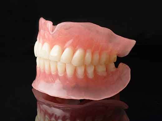 A full set of dentures on a black reflective surface
