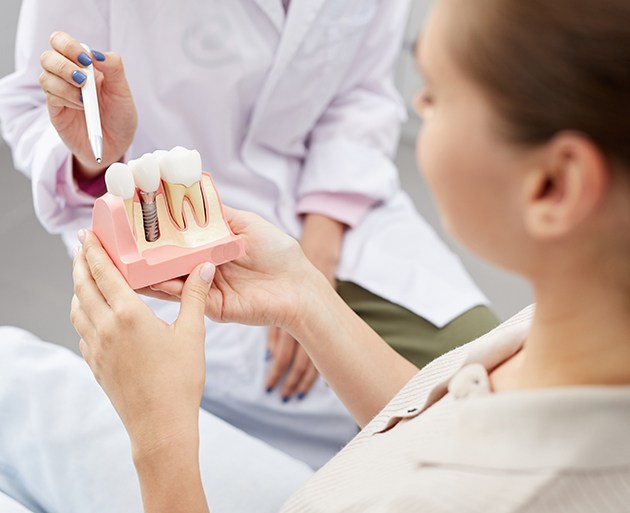 Dentist pointing to model of dental implant