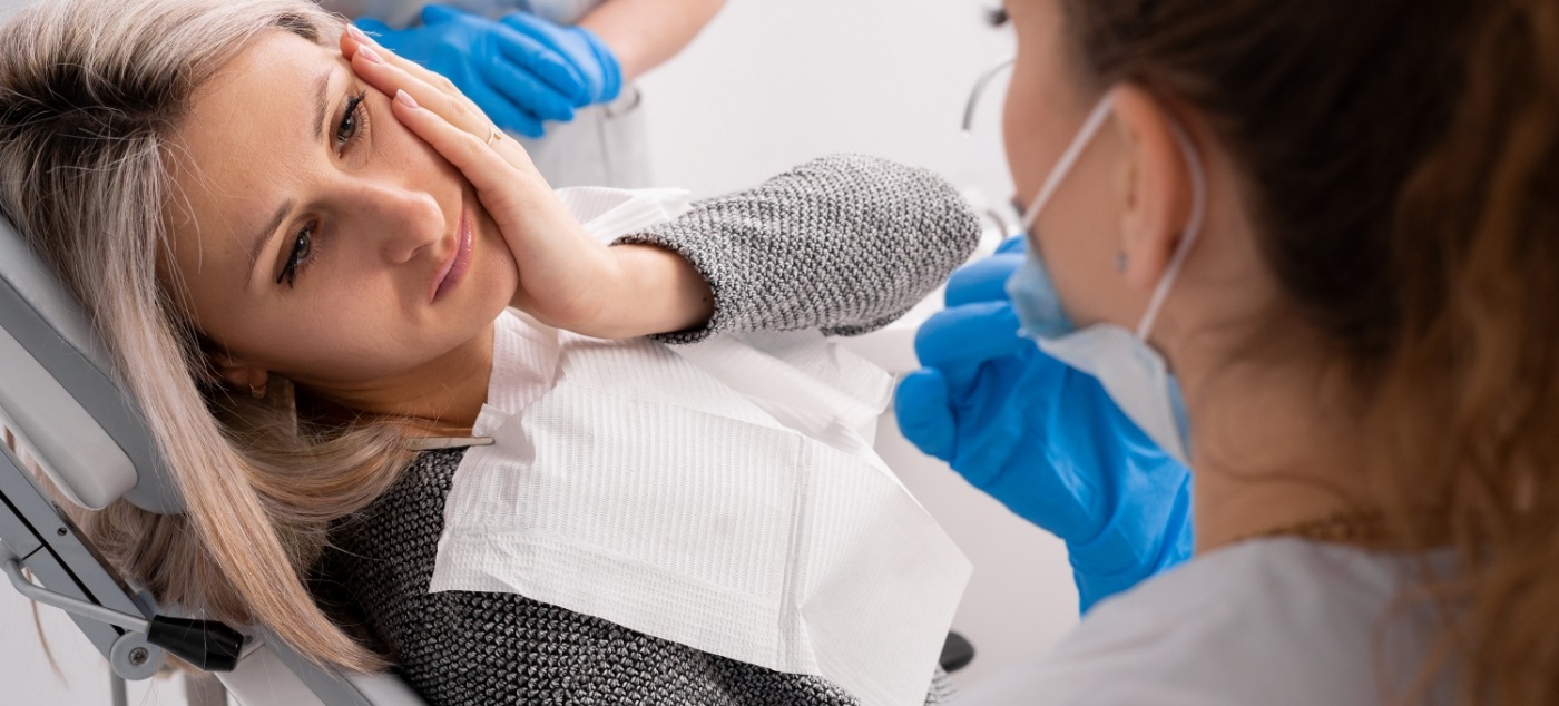 Woman holding her cheek in pain while talking to emergency dentist in Dublin