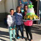 Three people smiling and holding a large cake