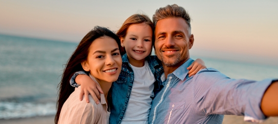 Family of three taking selfie on the beach