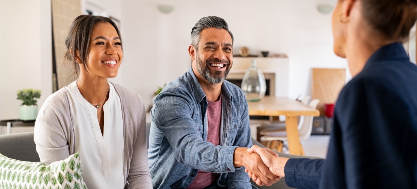 Man smiling and shaking hands with person across table