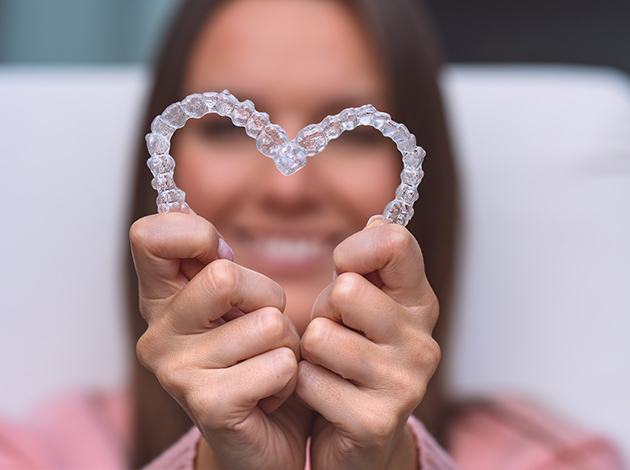 Woman holding Invisalign in the shape of a heart