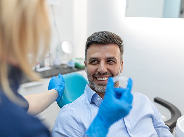 Dentist in blue gloves preparing to give Invisalign to patient