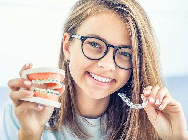 Girl holding sample braces in one hand and Invisalign in the other
