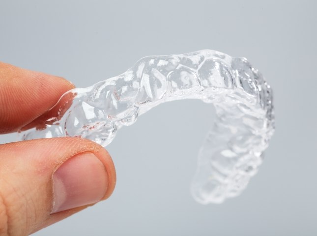 Hand holding an Invisalign clear aligner