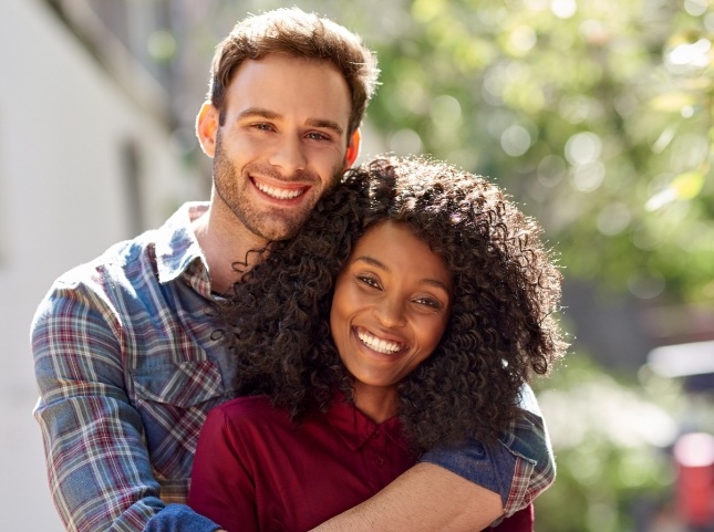 Young man and woman embracing outdoors