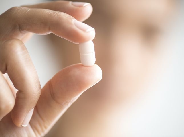 Hand holding a white pill