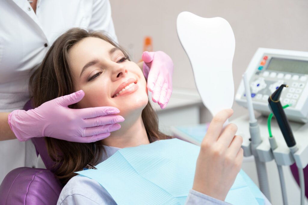 Woman in dental chair admiring her cosmetic treatment results