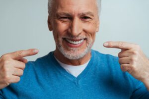 Man with dentures pointing to his smile